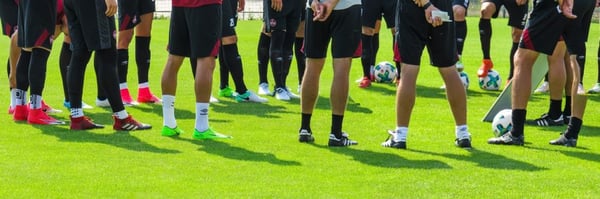 Team of football players standing listening during training session